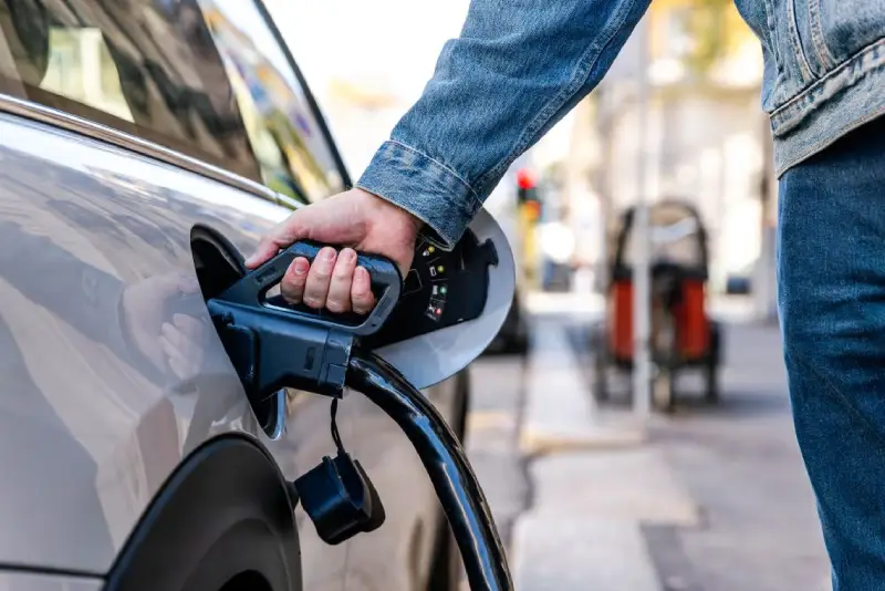 Conducteur rechargeant un véhicule moderne dans un environnement confortable